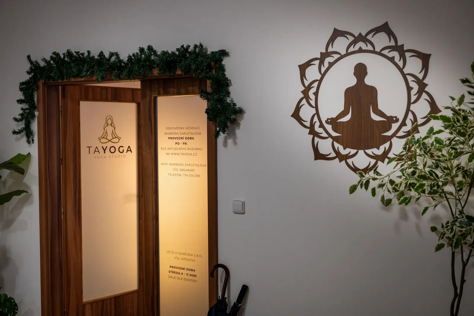 Dveře do studia s logem TaYoga a provozními informacemi na skle, vedle na stěně dřevěná mandala